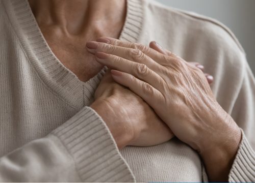 Woman with heart disease holding her chest knowing she must see a doctor in Fullerton