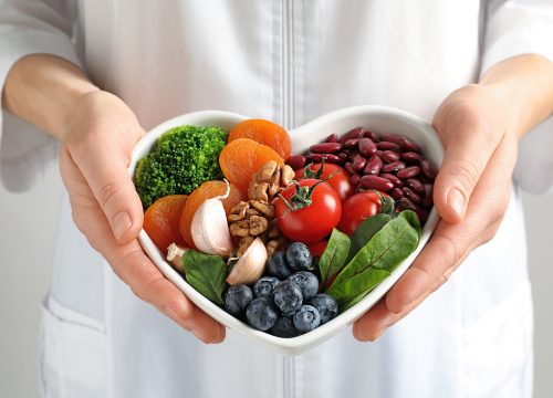 Woman holding heart shaped bowl of healthy foods to show Nutritional Counseling in Fullerton CA