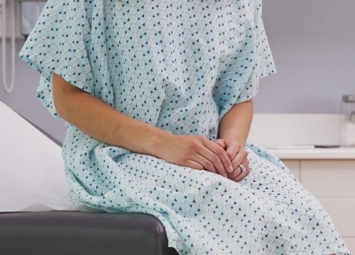 Woman sitting on exam table waiting for Palliative Care appointment with doctor in Fullerton CA