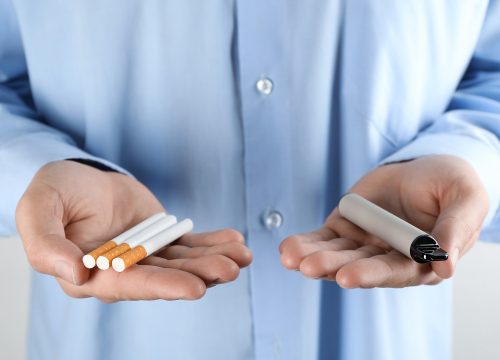 Man holding vape and cigarettes to show Smoking Cessation for Tobacco and Vaping in Fullerton